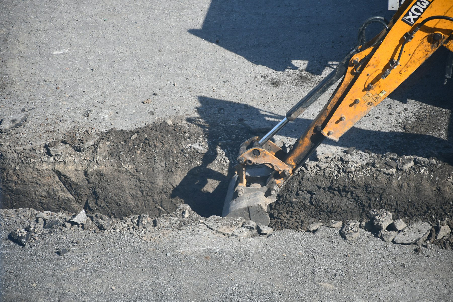 Excavator opening a trench for underground conduit